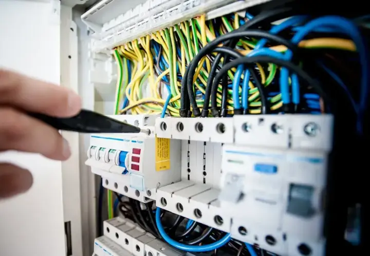 Elektryk sprawdza bezpieczniki w rozdzielnicy. Zastanawiasz się, jaki bezpiecznik do lodówki będzie najlepszy?