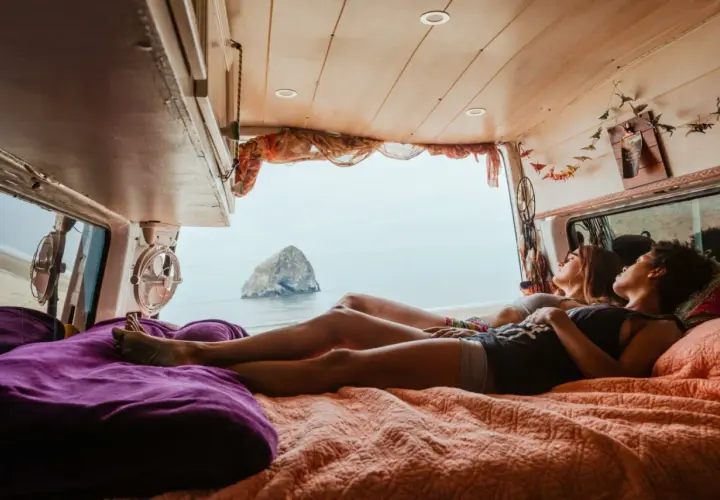 Deux amies profitent d'une vue imprenable sur la mer depuis leur spot van en Normandie.