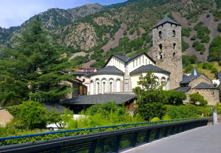 La parroquia de Escaldes-Engordany, con su torre románica, se alza majestuosa entre montañas verdes y edificios tradicionales.