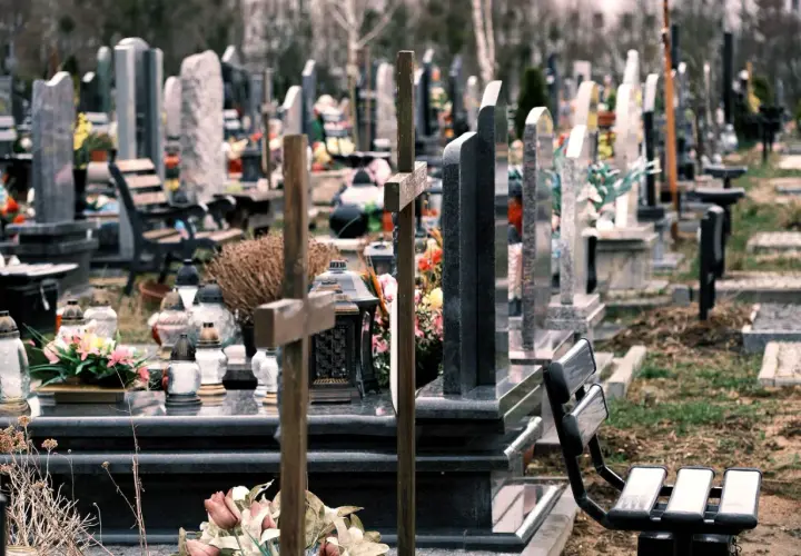 Cmentarz z nagrobkami i krzyżami. W oddali widać drzewa. Co oznacza RIP na pomniku? To skrót od łacińskiego "Requiescat in pace", czyli "Niech spoczywa w pokoju".
