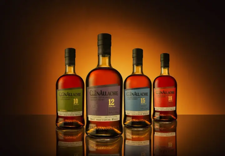 Cztery butelki whisky GlenAllachie, od 10 do 18 lat, z wyblakłymi etykietami, ukazujące skutki trzymania butelki whisky w nasłonecznionym miejscu.