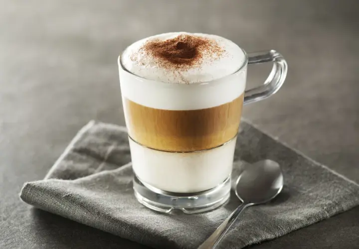Idealne latte macchiato proporcje: mleko, espresso i pianka tworzą apetyczne warstwy. Posypane kakao.