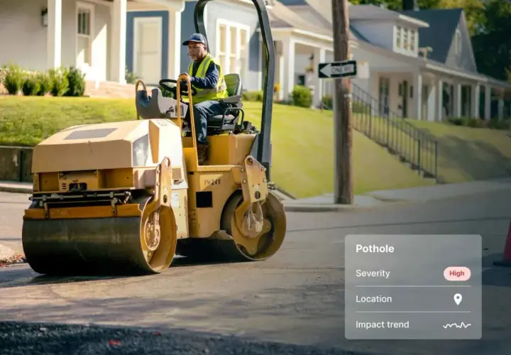 A worker operates a steamroller, ready to be a change agent and fix the high-severity pothole on this street.