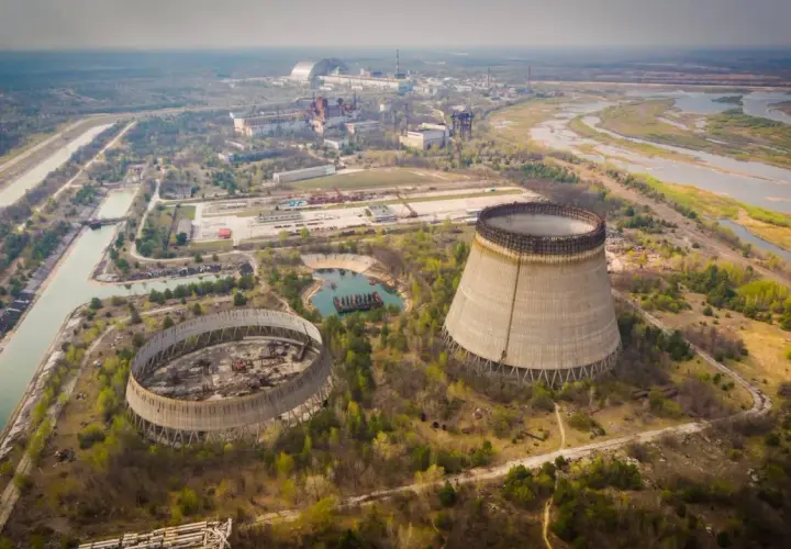 Opuszczone chłodnie kominowe elektrowni atomowej, które miały działać, gdy wybuchł Czarnobyl. W tle widać kompleks budynków i rzekę.