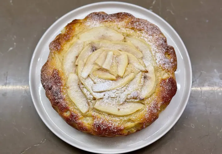 Torta ricotta e pere dorata, con fette di pera disposte a raggiera e spolverata di zucchero a velo.