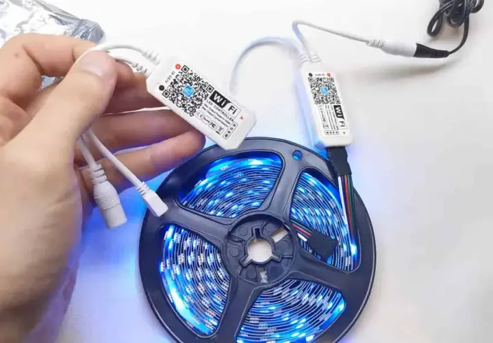 Ręka trzymająca kontroler Wi-Fi do taśmy LED. Dowiedz się, jak zresetować pilot do ledów, skanując kod QR.