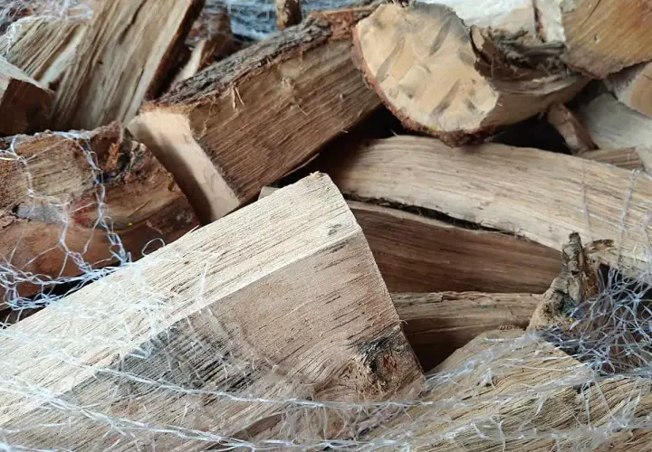 Gros plan sur un poids stère de bois sec, emballé dans un filet blanc, prêt pour l'hiver.