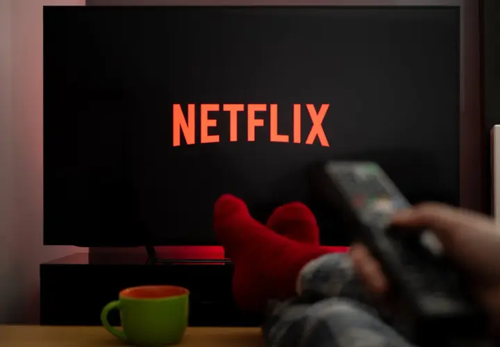 Relaks przy **Netflix w Play**. Czerwone skarpety, kubek i pilot w dłoni zapraszają do seansu.