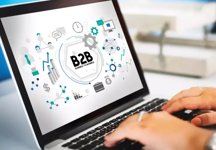Grafika na ekranie laptopa przedstawia schemat B2B, symbolizujący współpracę biznesową, z ikonami sieci, wykresów i komunikacji.