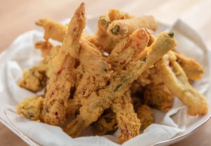Crispy, golden-brown vegetable sticks coated in a light, airy gluten free tempura batter, served in a white bowl lined with a napkin.