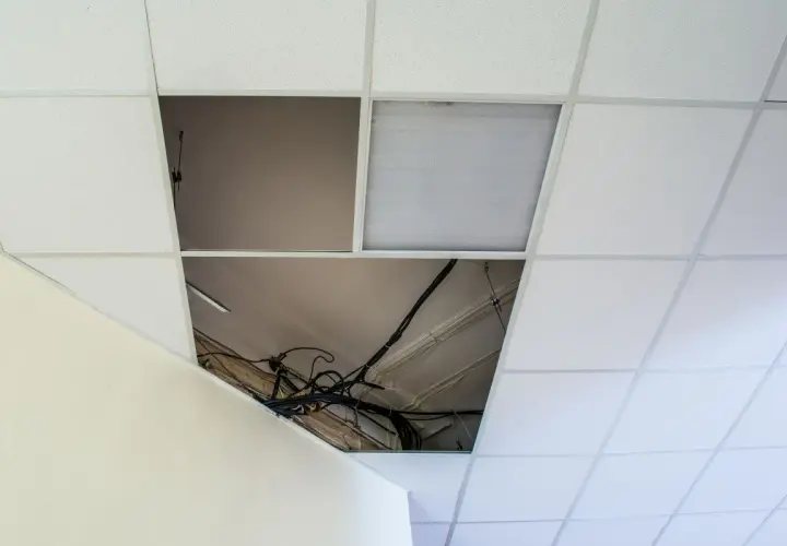 Schema distanza montanti controsoffitto cartongesso: cavi elettrici a vista in un'apertura del controsoffitto modulare.