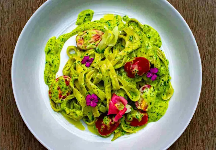 Tagliatelle fresche condite con un cremoso pesto di zucchine, pomodorini e fiori eduli.
