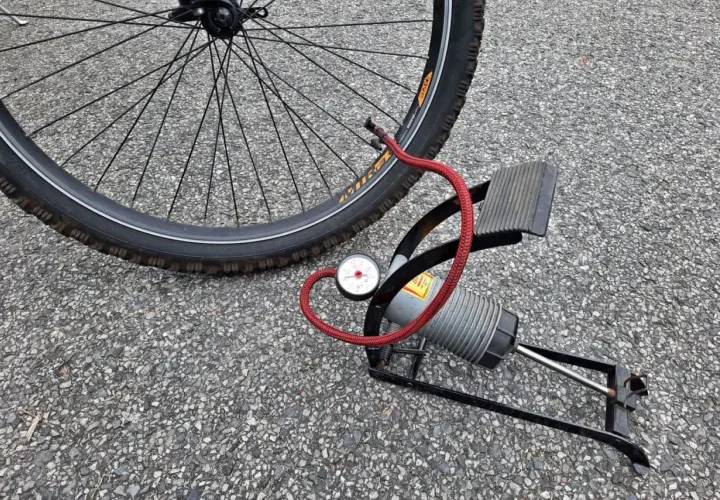 Pompka rowerowa z manometrem obok koła. Sprawdź ciśnienie w oponach rowerowych, tabela pomoże Ci dobrać odpowiednie.