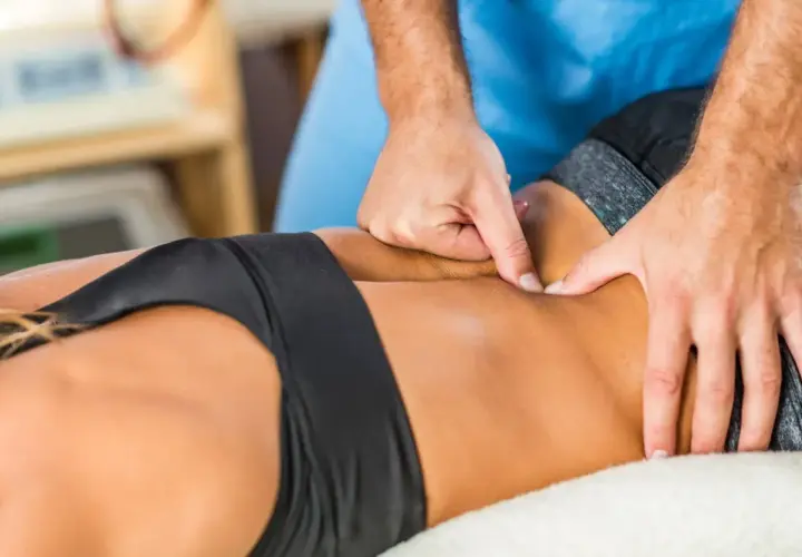Mains d'un thérapeute massant le bas du dos d'une femme. Un excellent massage pour mal de dos.