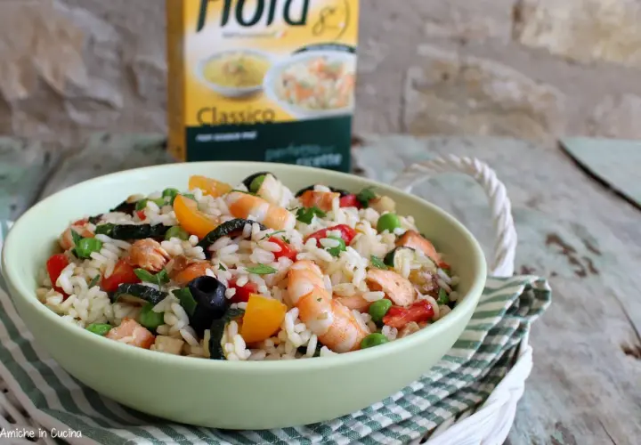 Un'appetitosa insalata di riso con pesce, gamberi, verdure e olive nere, pronta per essere gustata.