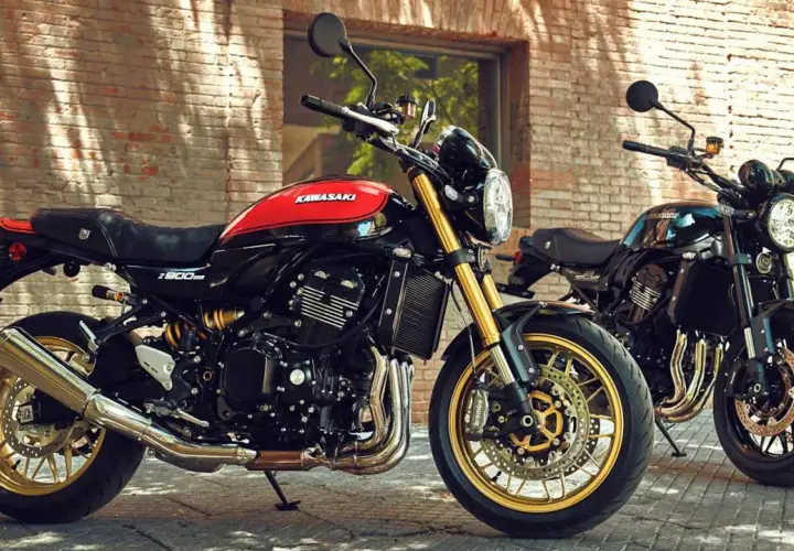 Zwei Kawasaki Z900RS, ein retro Motorrad in Schwarz-Rot, und ein weiteres in Schwarz, stehen vor einer Ziegelwand.