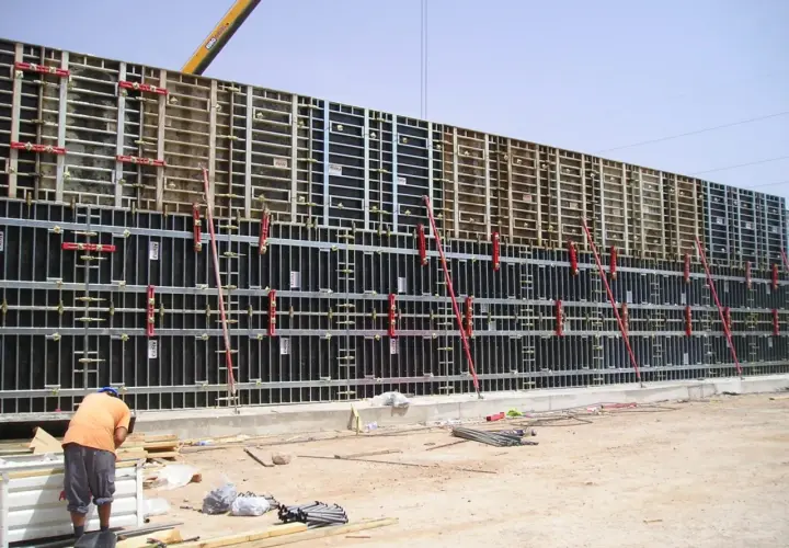 Un ouvrier travaille sur un grand petit coffrage béton, prêt pour le coulage. La structure métallique est impressionnante.