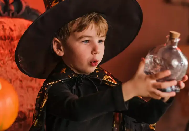 Niño mago con sombrero y capa, sosteniendo una botella con forma de calavera. ¡Perfecto para trucos de magia para niños de 3 a 6 años!