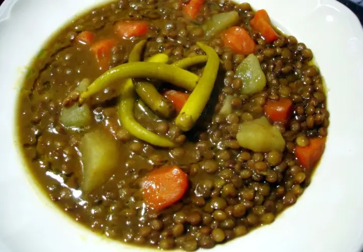 Un plato de lentejas con verduras, patatas y guindillas verdes. Un guiso reconfortante y nutritivo.