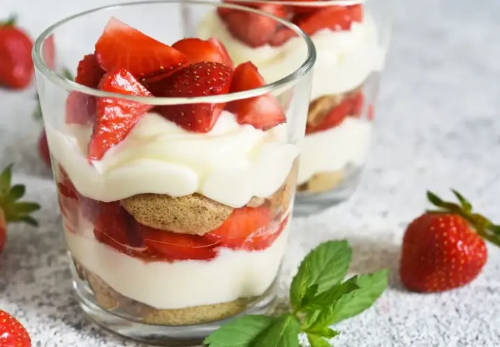 Un délicieux dessert léger aux fraises, alternant biscuits, crème onctueuse et fruits rouges frais, servi dans des verres.