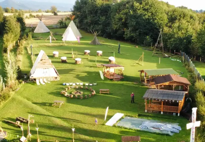 Wioska indiańska w Lubelskiem z tipi, drewnianymi chatkami i miejscem na ognisko.