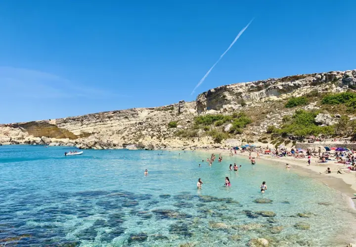 Słoneczny dzień w Paradise Bay na Malcie. Turkusowa woda, piaszczysta plaża i skaliste klify tworzą idylliczny krajobraz.