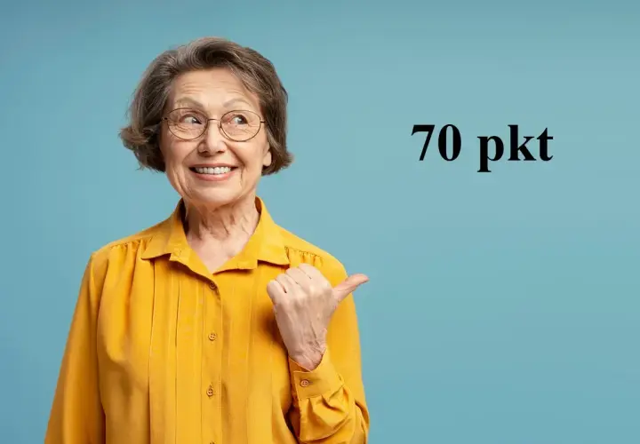 Uśmiechnięta starsza kobieta w okularach i żółtej bluzce wskazuje kciukiem na napis "70 pkt".