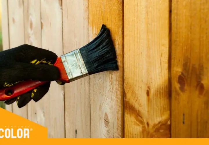 Mano enguantada aplica barniz a madera. Descubre con qué pintura se pinta la madera para protegerla y embellecerla.