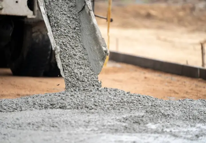 Gruszka betonu z betoniarki wysypuje się na plac budowy. Trudno ocenić ile m3 betonu jest wylewane.