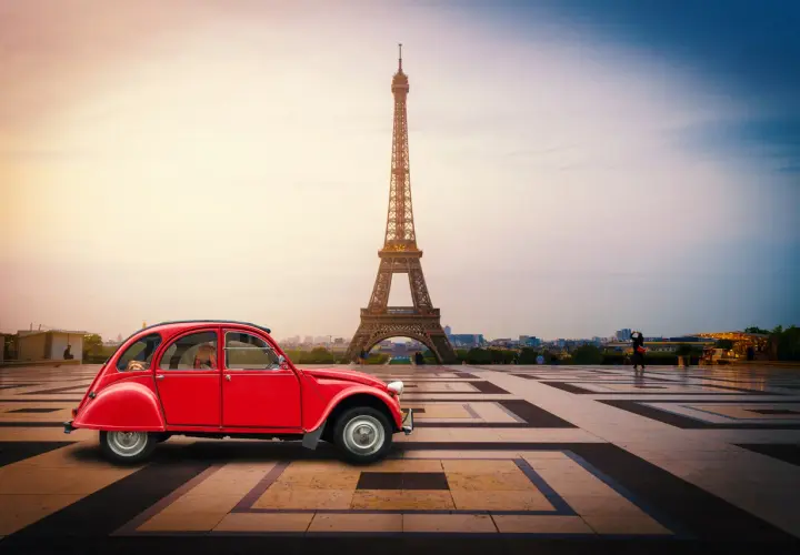Czerwony Citroën 2CV na tle Wieży Eiffla w Paryżu.