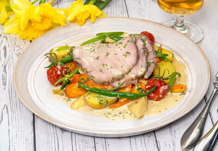 Skinkstek i ugn serverad med rotfrukter, gröna bönor och en krämig sås. En härlig vårmåltid.
