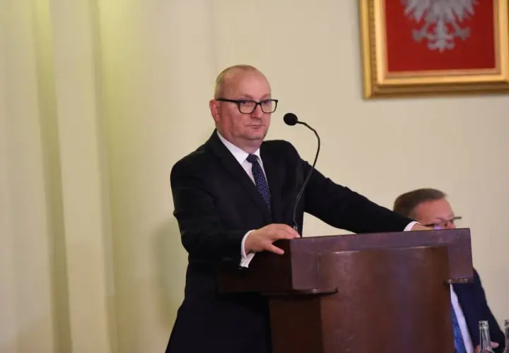 Mężczyzna w garniturze przemawia przy mównicy.