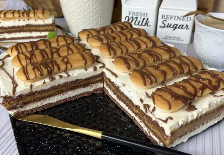 Pyszne ciasto z kajmakiem i mascarpone, udekorowane biszkoptami i czekoladą. Idealne na deser.