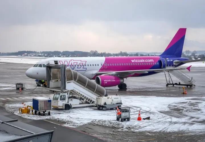Samolot Wizz Air na lotnisku zimą, z drabiną i sprzętem naziemnym.