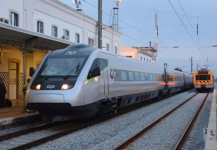 Tren moderno plateado y otro amarillo en estación, listos para el viaje de Lisboa a Oporto.