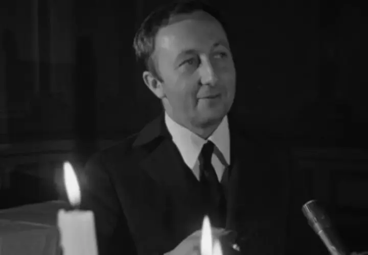 Bogumił Kobiela w jednym z filmów, w eleganckim garniturze, przy blasku świec.