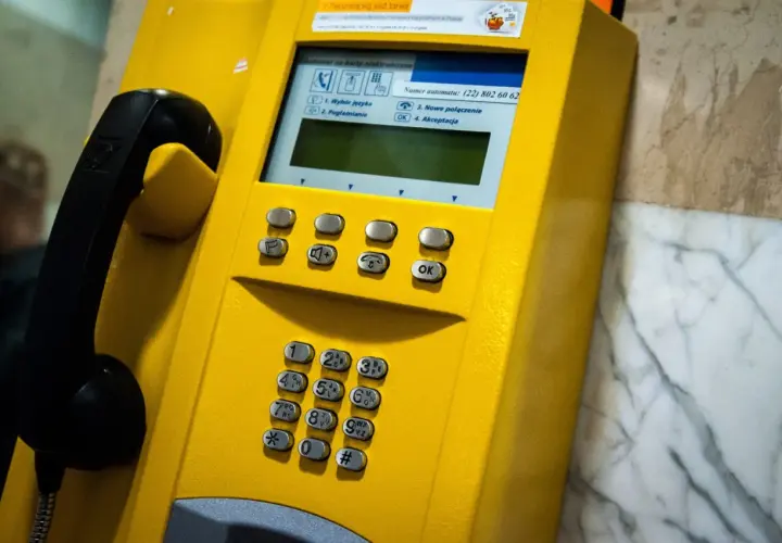 Żółta budka telefoniczna z numerem kierunkowy 94. Słuchawka czeka na połączenie.