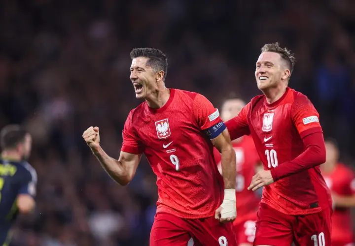 Piłkarze w czerwonych koszulkach świętują bramkę. Lewandowski z numerem 9 i jego kolega z numerem 10, duma klubu wybitnego reprezentanta.
