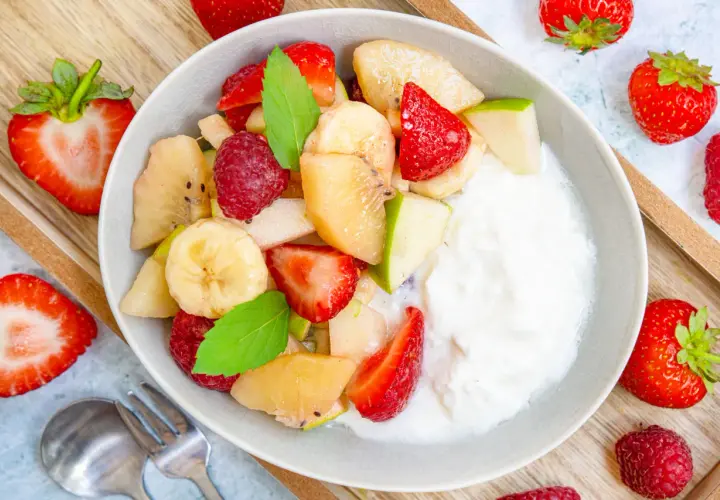 Frischer Obstsalat mit Joghurt, Erdbeeren, Bananen, Äpfeln und Himbeeren. Ein einfaches obstsalat rezept für jeden Tag.