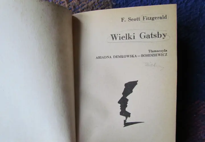 Strona tytułowa "Wielkiego Gatsby'ego" F. Scotta Fitzgeralda. Czarno-biała grafika profilu twarzy.