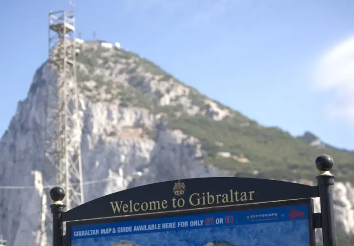 Tablica "Welcome to Gibraltar" przed skalistym zboczem. Czy Gibraltar to państwo? Mapa i przewodnik dostępne za 1 funta lub 1 euro.