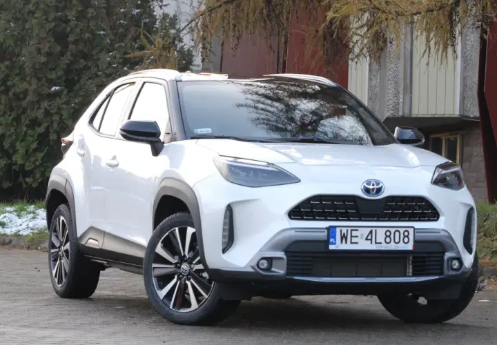 Biały Toyota Yaris Cross 2025 z czarnymi dodatkami, zaparkowany na zewnątrz.