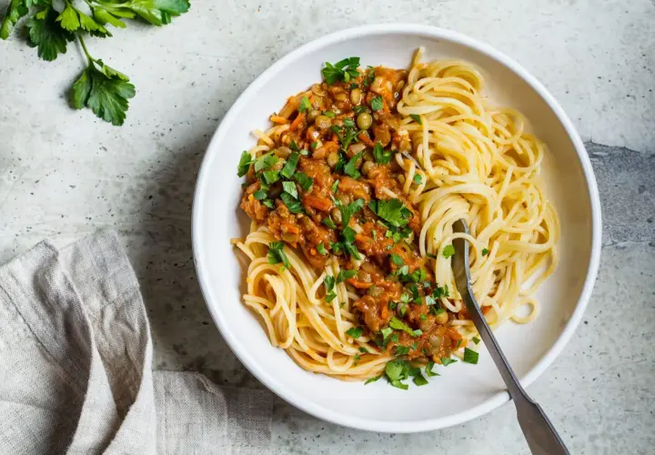 Spaghetti z sosem z soczewicy i warzyw, posypane natką. Idealne, gdy zastanawiasz się, jaki ser do spaghetti zamiast parmezanu.