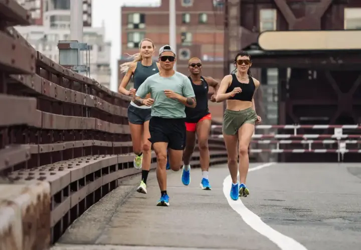 Grupa biegaczy na moście, wykonująca trening fartlek. Dynamiczne tempo i skupienie na osiągnięciu celu.
