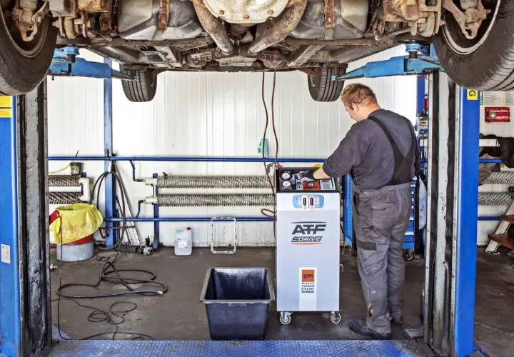 Mechanik wykonuje dynamiczną wymianę oleju w skrzyni biegów za pomocą specjalistycznego urządzenia.