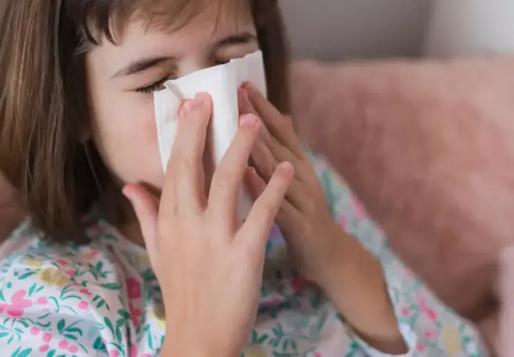 Dziewczynka z chusteczką przy nosie, być może potrzebuje antybiotyku na zatoki.