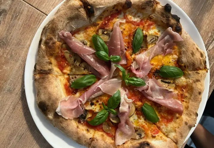 Pyszna pizza z szynką parmeńską i bazylią. Zastanawiasz się, ile kosztuje pizza w Chorwacji? Ta wygląda na wartą swojej ceny!