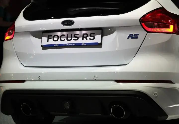 Biały Ford Focus RS z niebieskim znaczkiem RS i podwójnymi końcówkami wydechu.