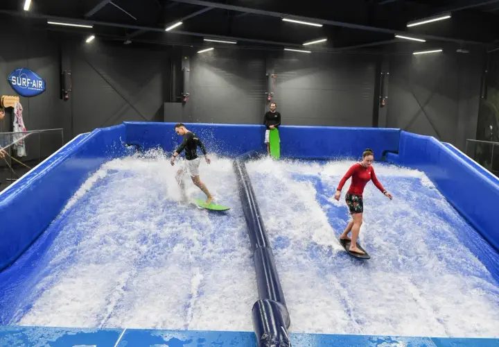 Ludzie surfują na sztucznej fali w Surf-Air, największym aquaparku w Polsce.