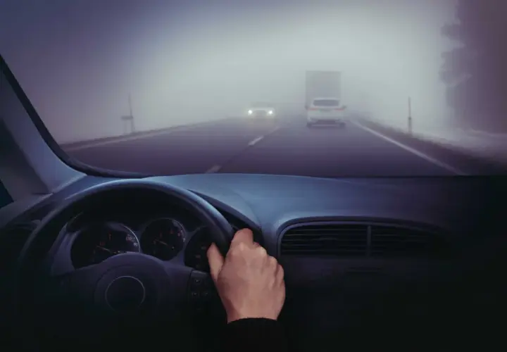 Conduciendo en carretera con poca visibilidad por niebla. Hay poca visibilidad por niebla, ¿qué debe hacer? Reducir velocidad y usar luces antiniebla.